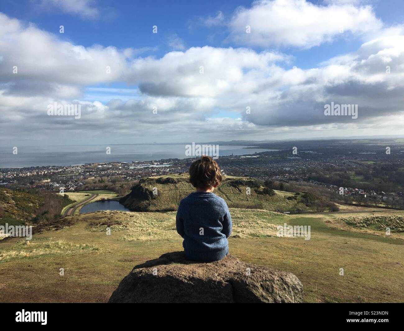 Junge sitzt am Arthur's Seat, Edinburgh Stockfoto