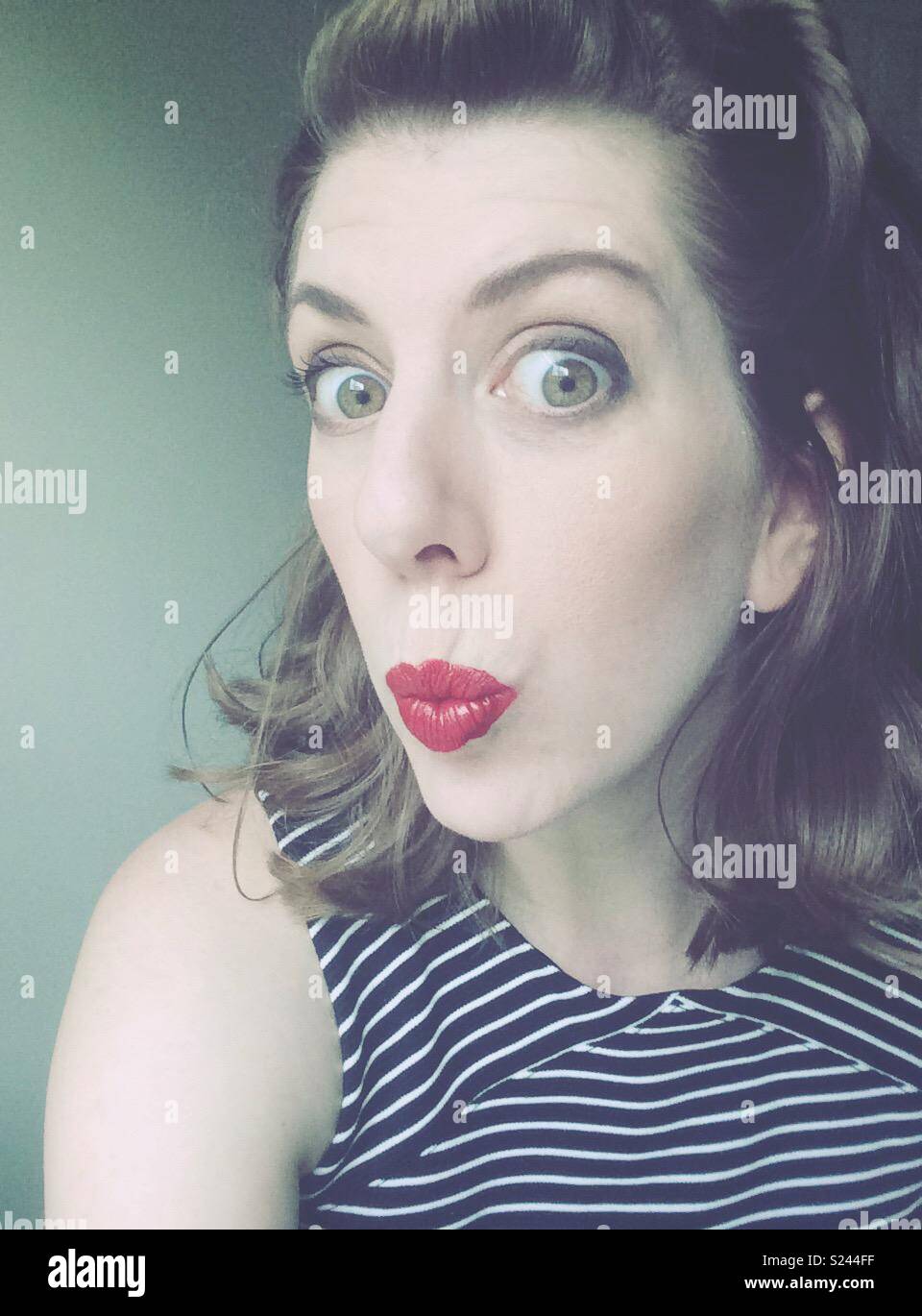 Frau mit großen Augen und kissy Gesicht mit roten Lippenstift Stockfoto