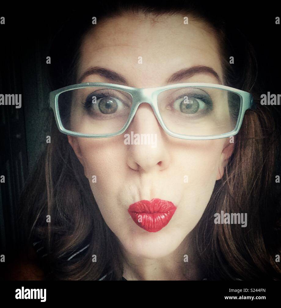 Frau mit silber Gläser und große Augen und roten hochgestülpten Lippen Stockfoto