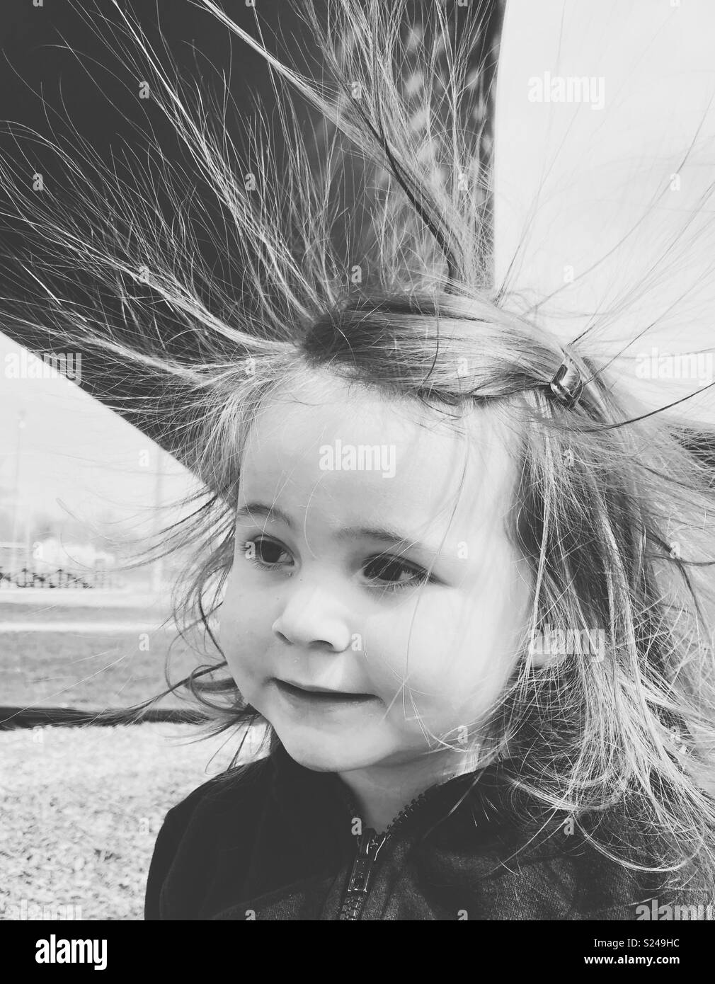 Schwarz-weiß Bild von Toddler girl an der Seite Suchen mit Haar durch statische Elektrizität klemmt Stockfoto