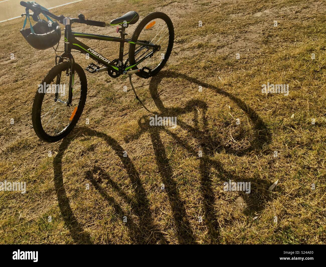 Fahrrad mit Helm im Sonnenschein auf Gras mit langen Schatten Stockfoto
