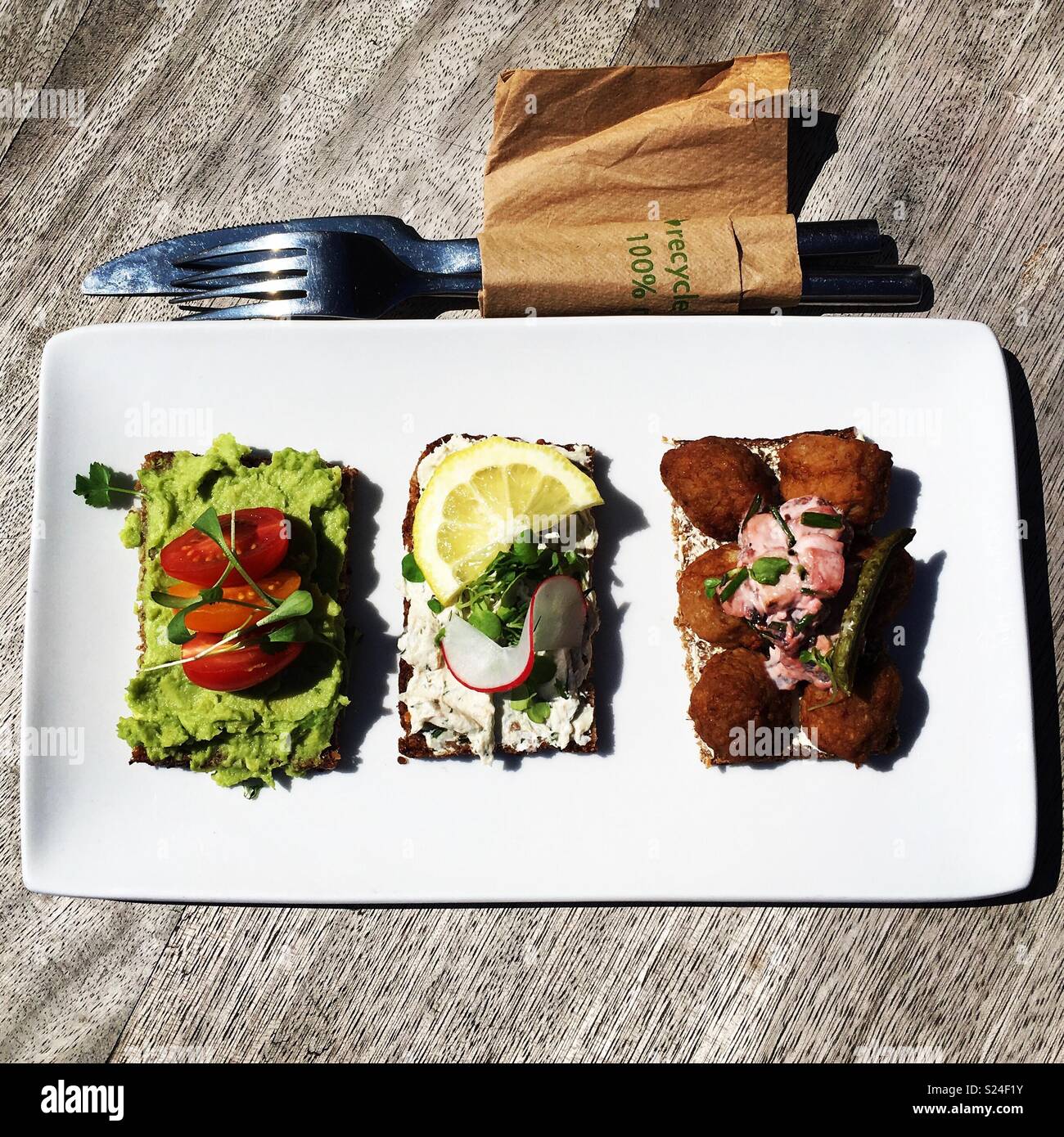 Eine Auswahl von drei verschiedenen Sandwiches auf einem weißen rechteckigen Platte neben eine Gabel und Serviette Stockfoto