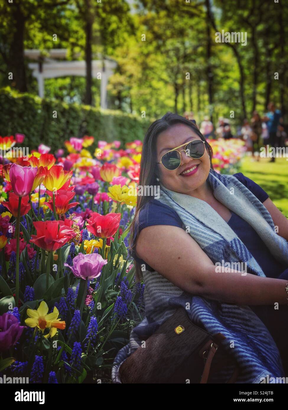 Eine Dame posiert für ein Foto in einem Garten. - Smartphone-aufgenommenes Stockfoto