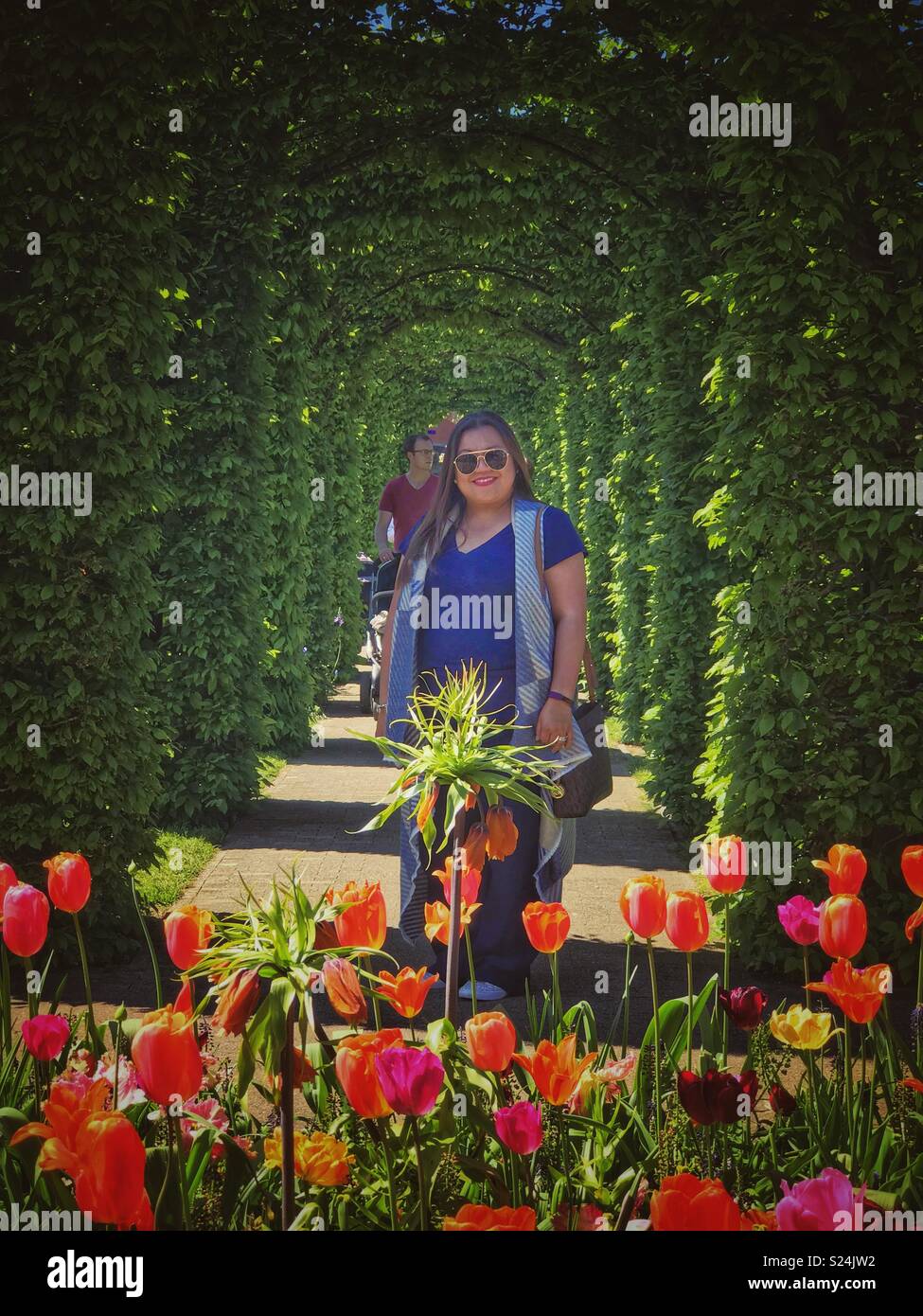 Eine Dame stellt für ein Portrait in einem Garten. - Smartphone-aufgenommenes Stockfoto