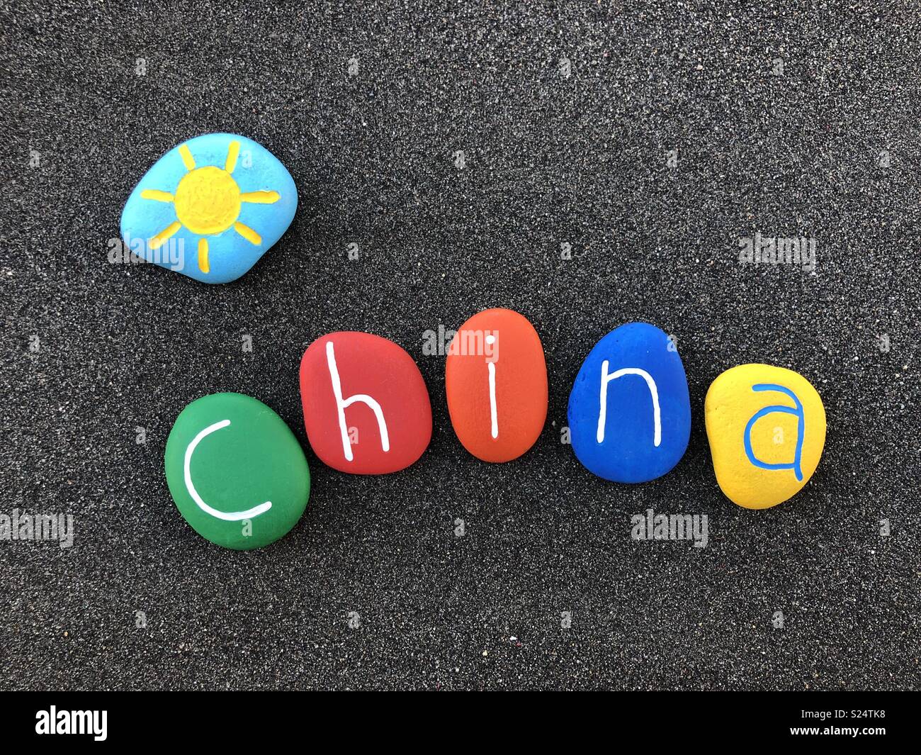 China, Souvenir mit bunten und geschnitzte Steine über schwarzen vulkanischen Sand Stockfoto