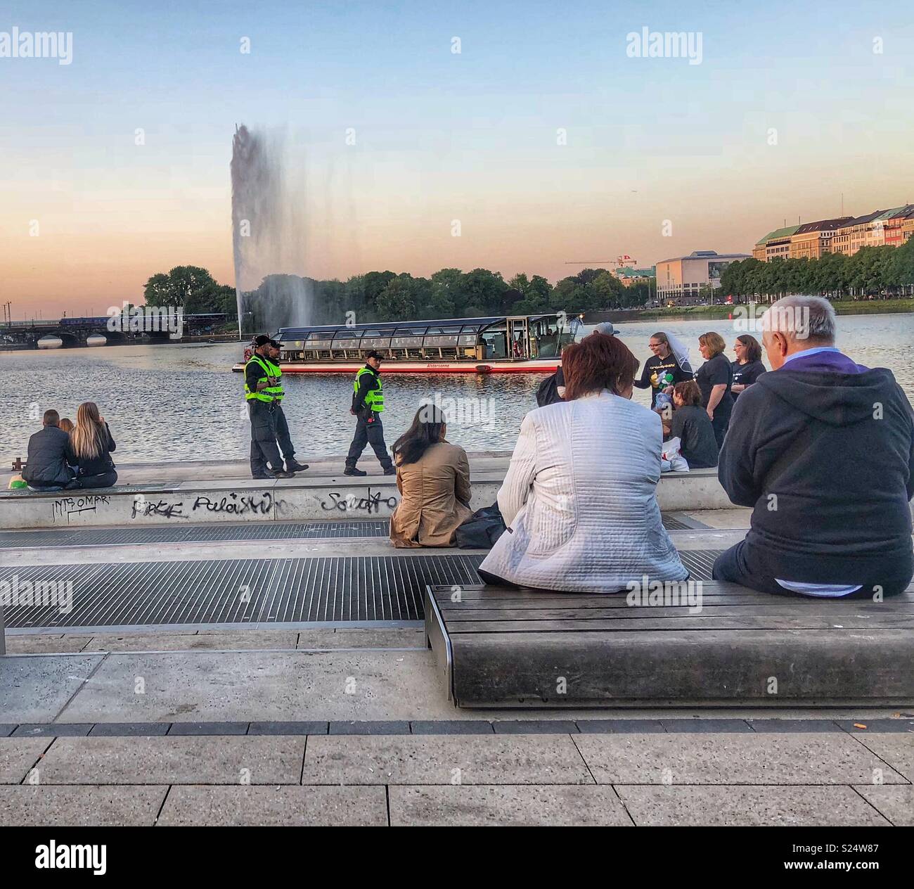 Touristen, Einheimischen und der Polizei erleben Sie den Sonnenuntergang rund um den See der Stadt - Binnenalster in Hamburg, Deutschland. Stockfoto