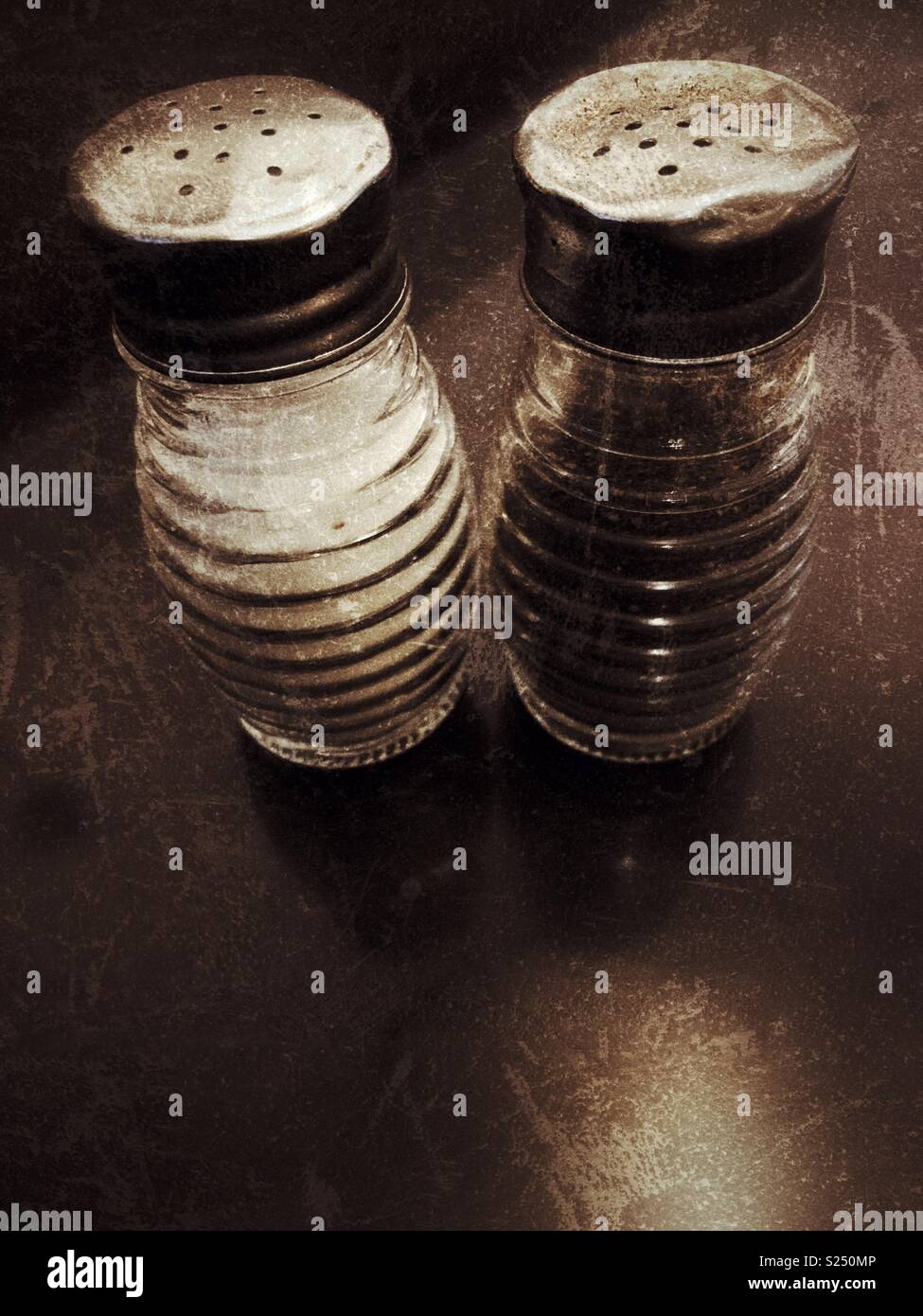 Alte Glas Salz- und Pfefferstreuer mit Verbeulten Metalldeckel Stockfoto