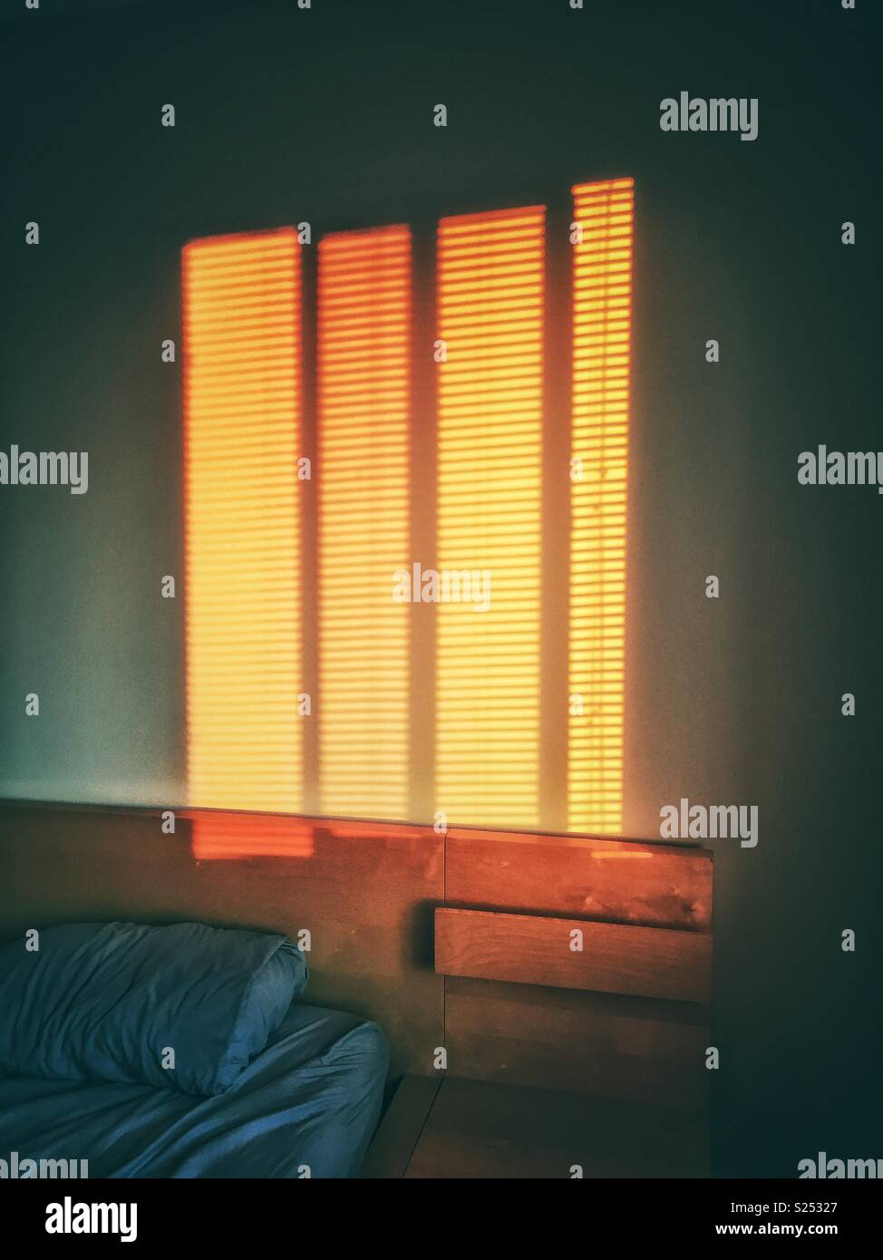 Brilliant orange Muster auf Schlafzimmer Wand von Sonnenaufgang scheint durch Jalousien. Stockfoto