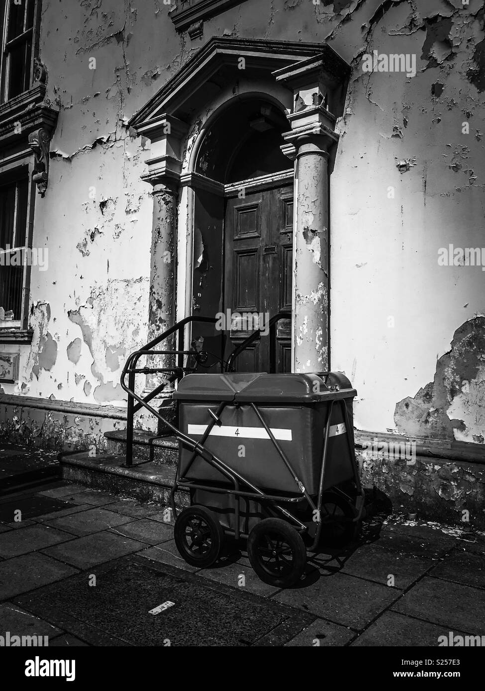 Post Trolley angekettet an Geländer vor der Eingangstür in schlechtem Zustand Stockfoto