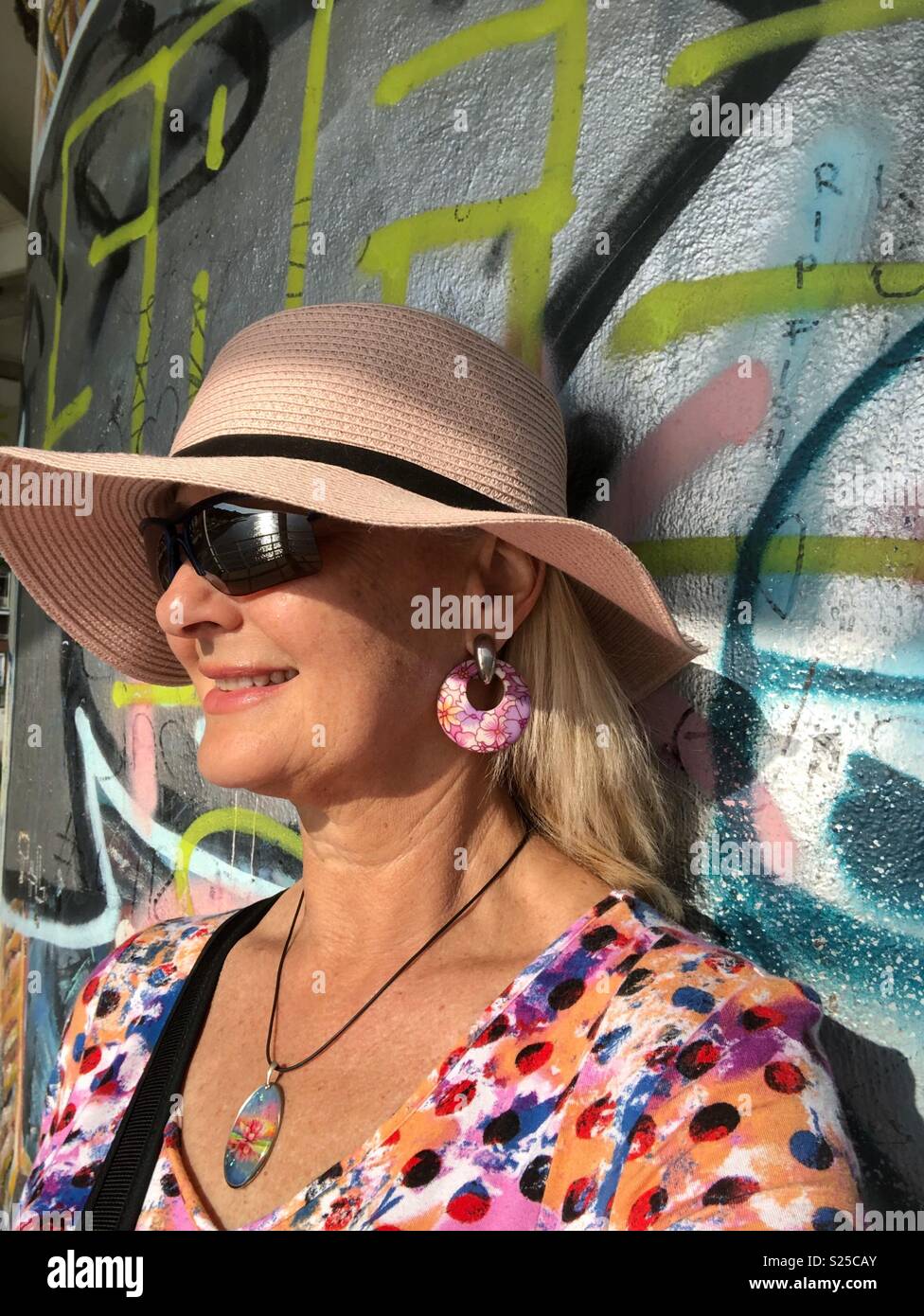 Frau lehnte sich gegen ein Graffiti an der Wand. - Smartphone-aufgenommenes Stockfoto