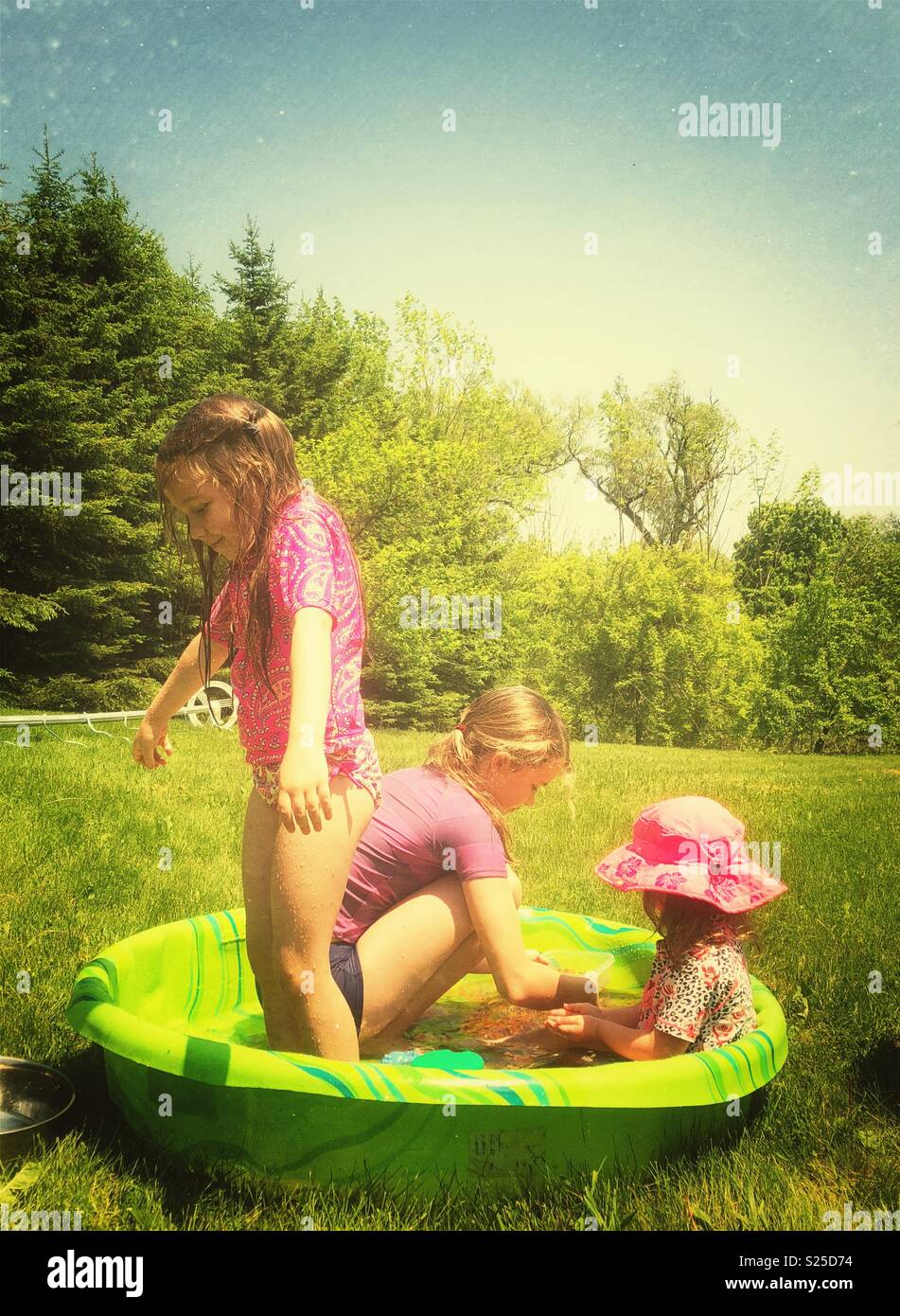 Drei Schwestern spielen in einem Hinterhof kiddy Planschbecken an einem heißen sonnigen Tag Stockfoto