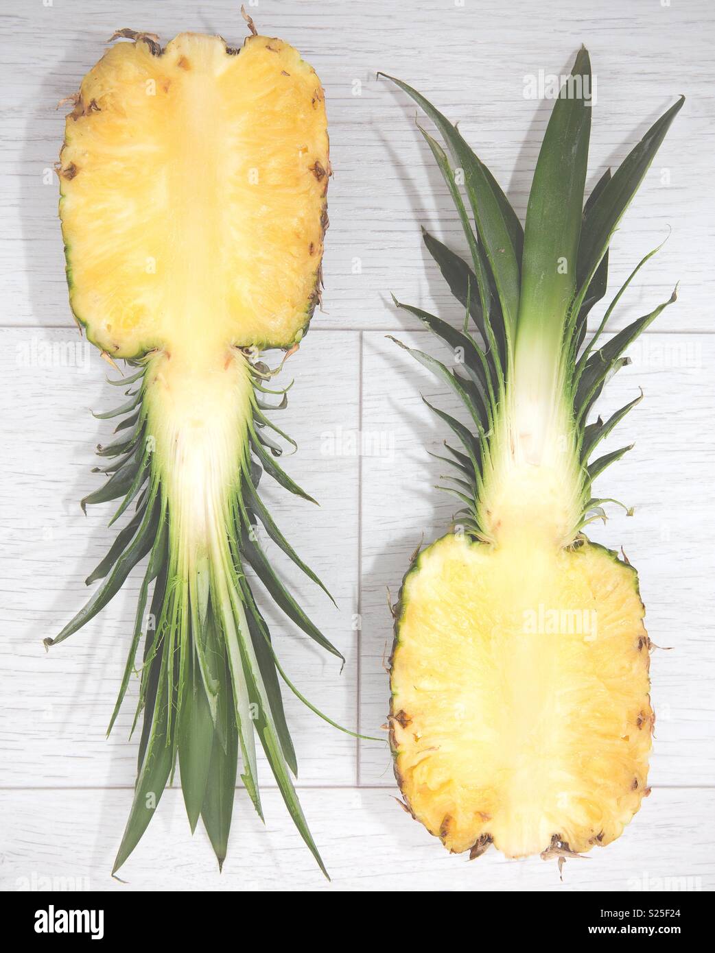 Eine saftige Ananas in der Hälfte von oben auf weißem Hintergrund - Smartphone-aufgenommenes Stockfoto