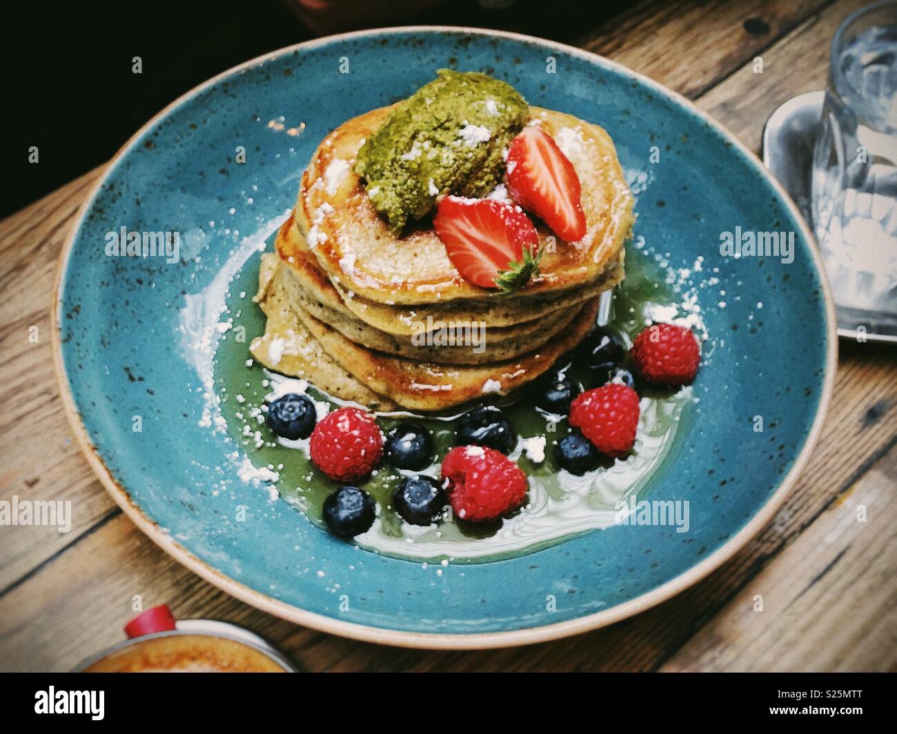 Pfannkuchen mit Beeren auf einem blauen Platte auf einem Holztisch Stockfoto