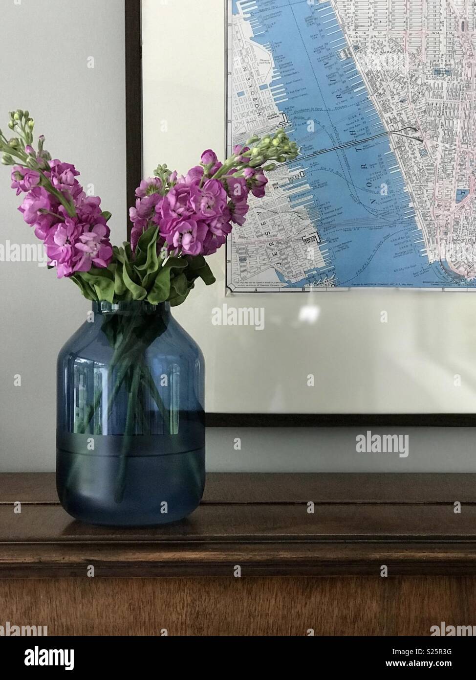 Blaue Vase, rosa Blüten und vintage Karte im Innenraum Vignette Stockfoto