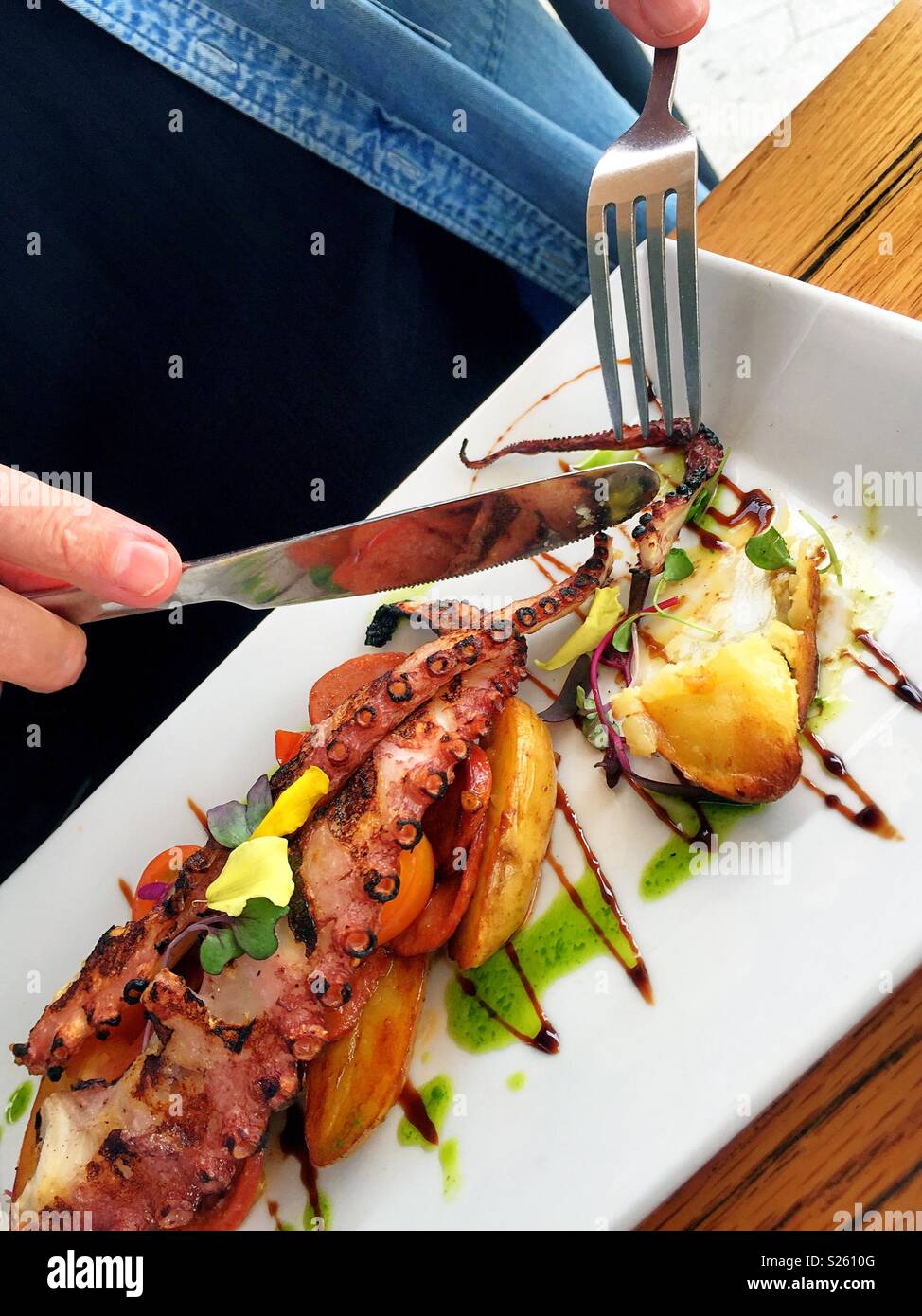 Mann in Gegrillter Tintenfisch und Chorizo entrée in einem Restaurant schneiden, USA - Smartphone-aufgenommenes Stockfoto