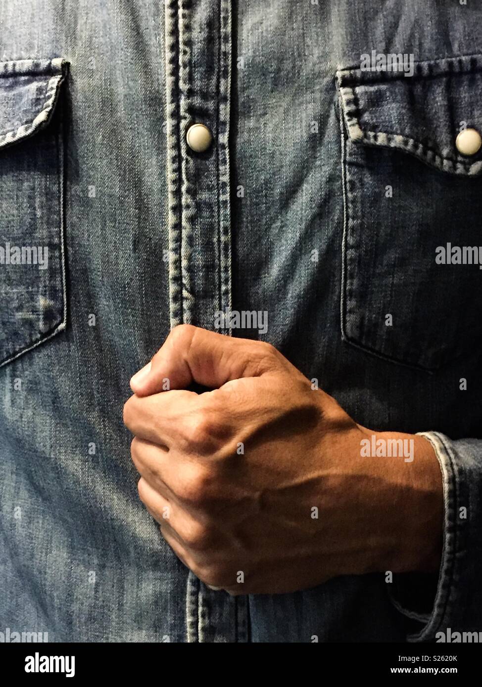 Geschlossene Faust mit einem jeanshemd - Smartphone-aufgenommenes Stockfoto