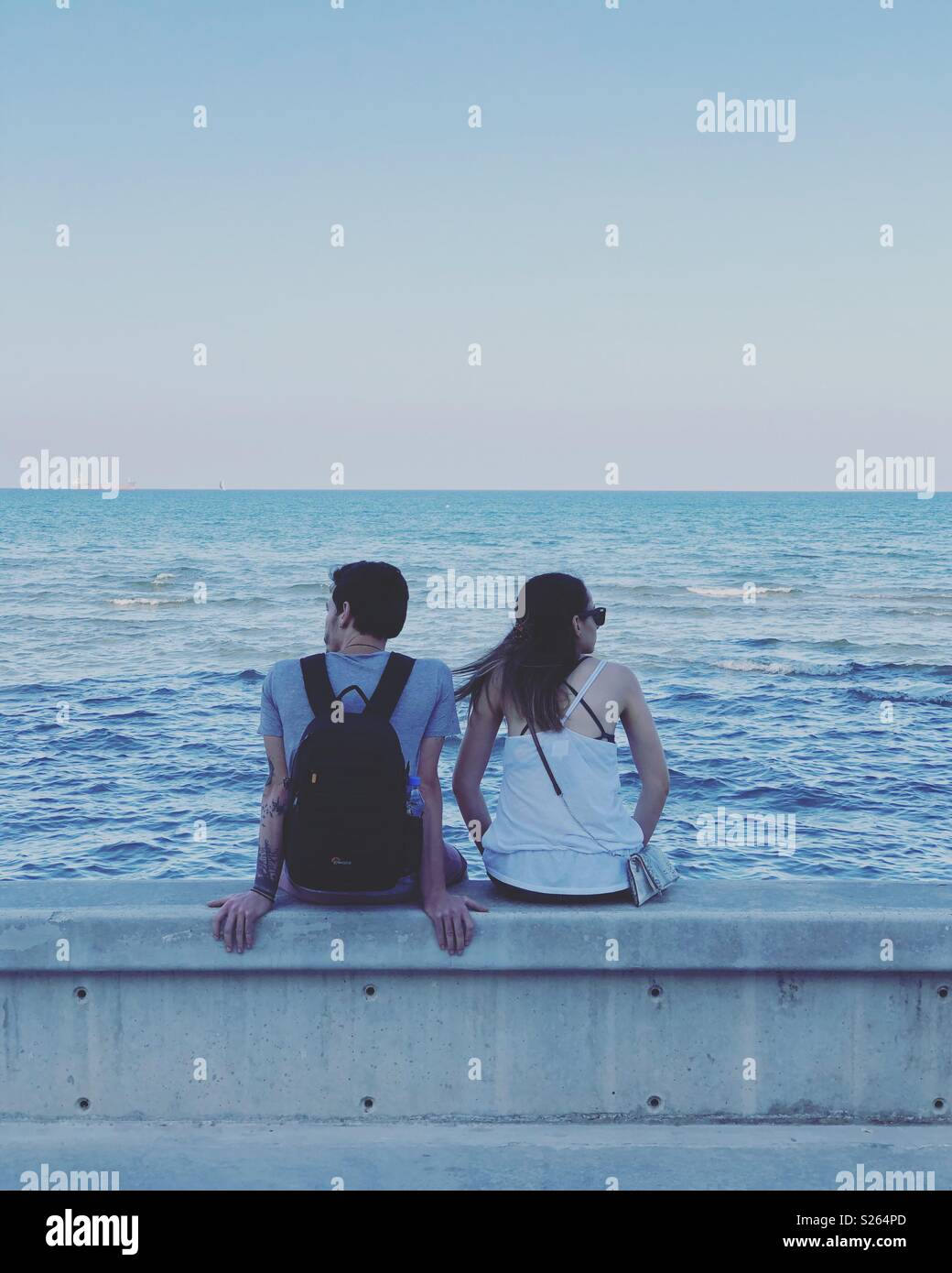 Paar saßen zusammen an einer Wand, die mit Blick auf das Meer. Stockfoto