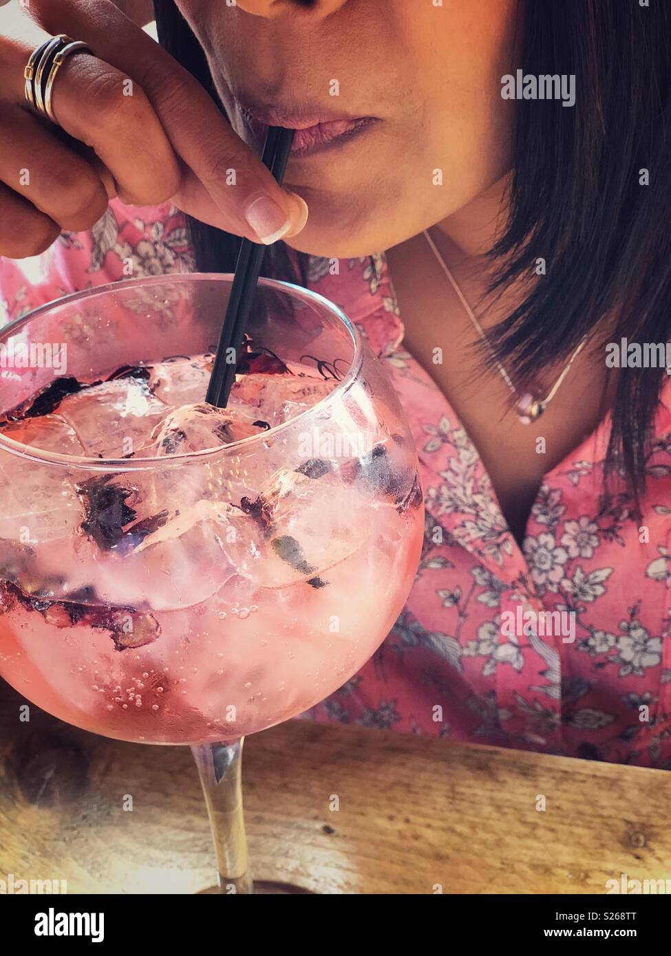 Frau getränke Pink Gin Tonic von einem Gin Glas. Stockfoto