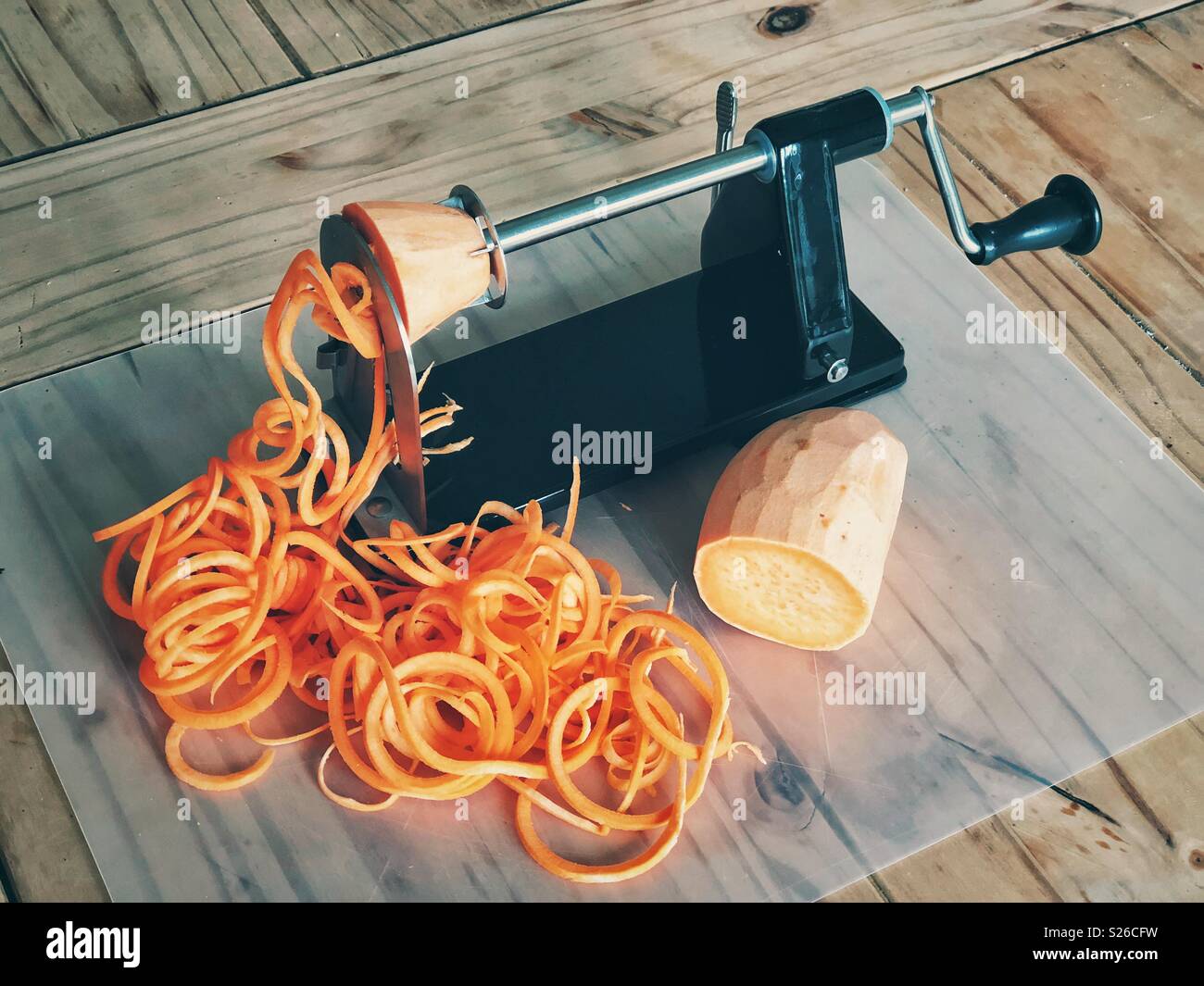 Spiralizing Kartoffel mit schwarzen spiralizer auf hölzernen Tisch Stockfoto