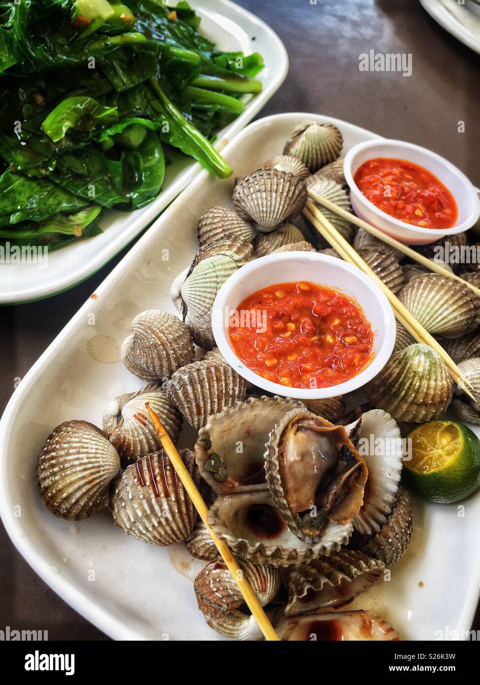 Muscheln und Chili Sauce mit Gai lan und Knoblauch an der East Coast Lagoon Food Village, eine Hawker Food Markt in Singapur Stockfoto