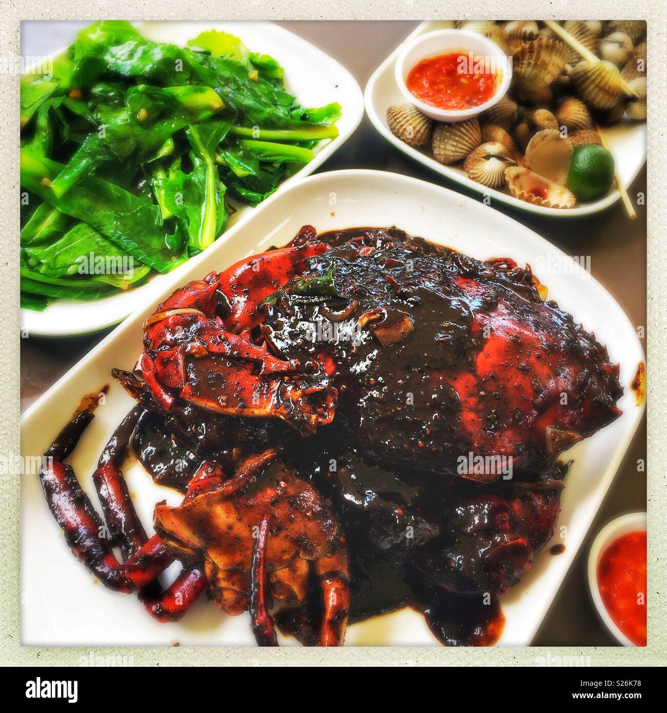 Schwarzer Pfeffer, Krabben, Muscheln mit Chili Sauce und Gai lan mit Knoblauch an der East Coast Lagoon Food Village, eine Hawker Food Markt in Singapur Stockfoto