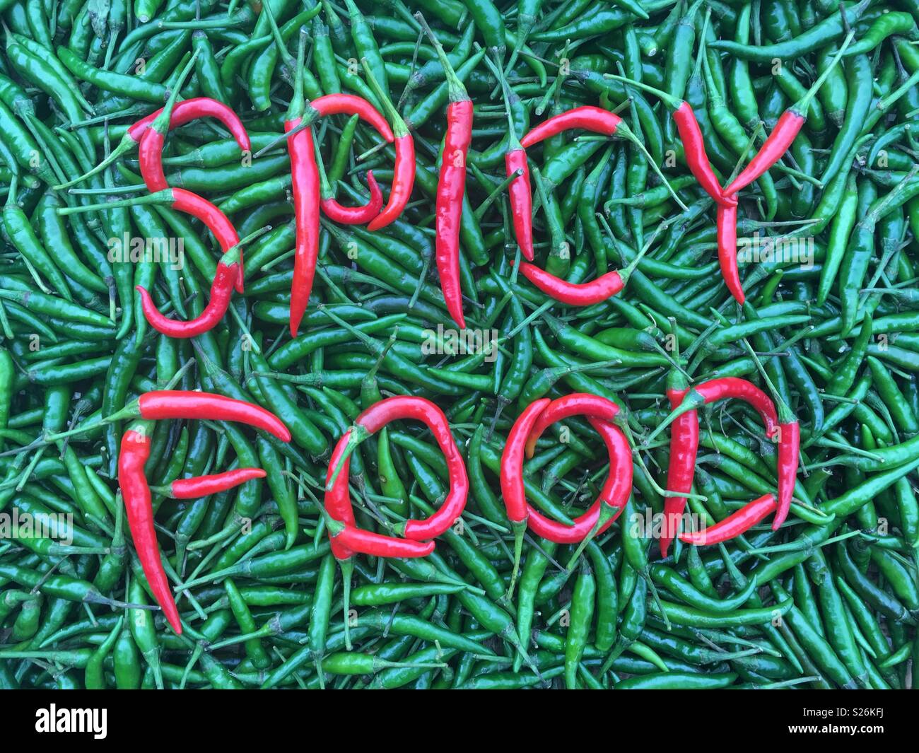 Die Wörter würzig essen' in rote und grüne Chilischoten geschrieben Stockfoto