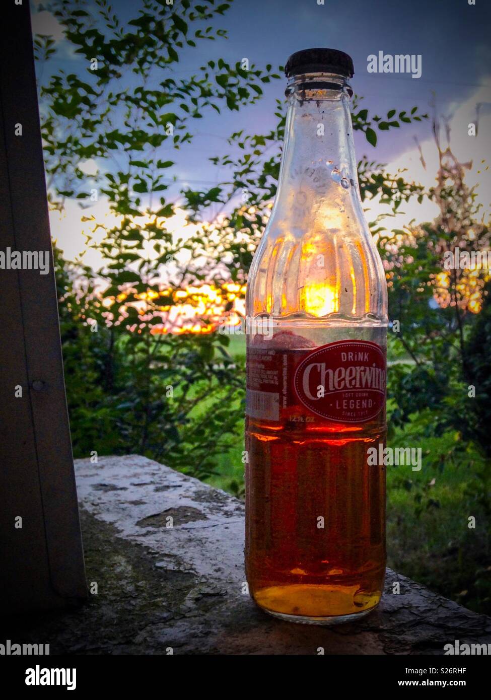 Lebendige Foto der ungeöffneten Flasche verdampft Cheerwine Fang den Sonnenuntergang von der Veranda Stockfoto