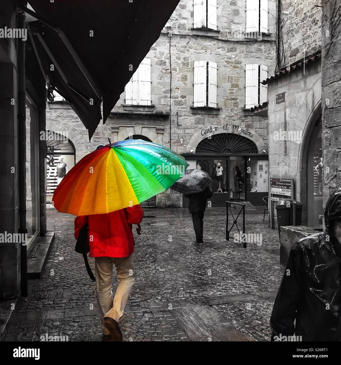 Figeac, Frankreich. Farbe pop Foto von Hellen regenbogenfarbenen Regenschirm an einem regnerischen Tag. Stockfoto