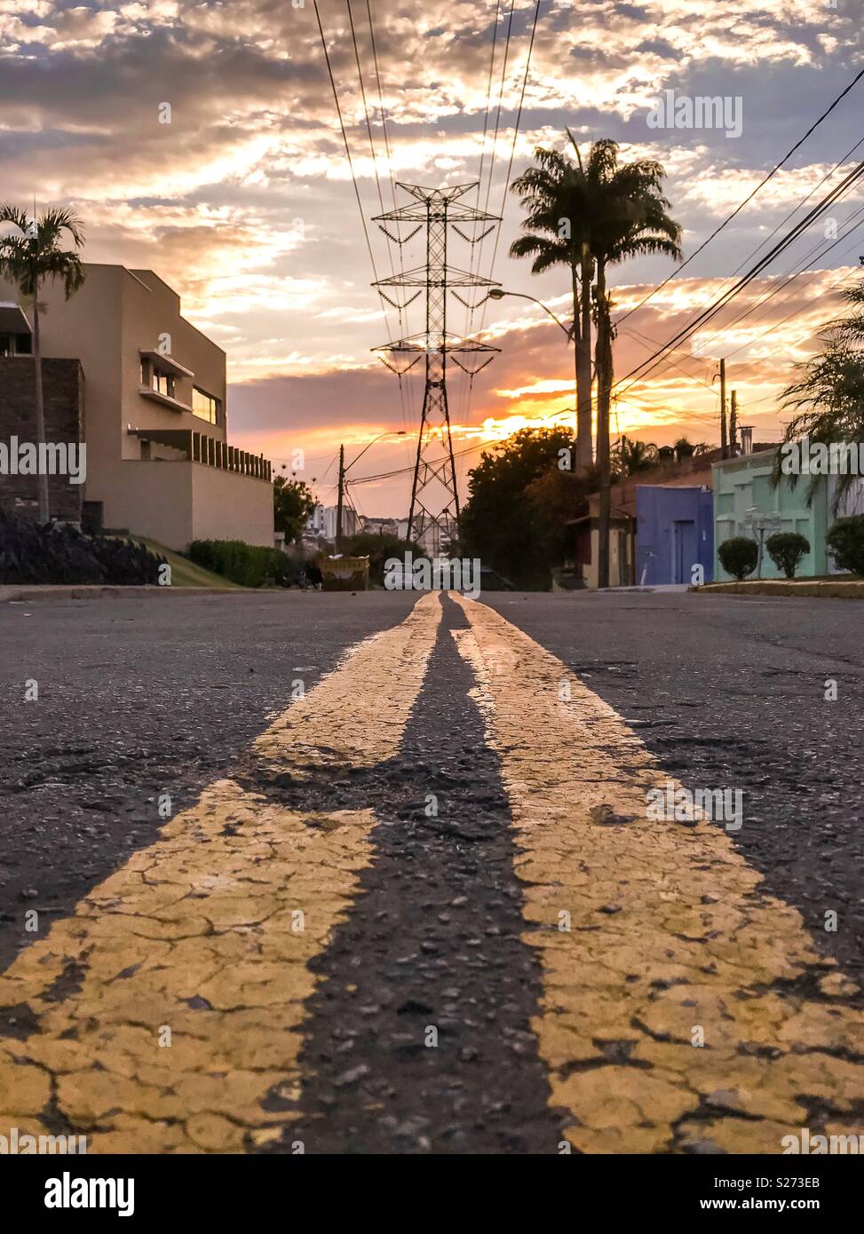 Doppelten gelben Linien auf der Straße, die zu einem power line Turm vor Sonnenuntergang in Campinas, SP/Brasilien - Smartphone-aufgenommenes Stockfoto