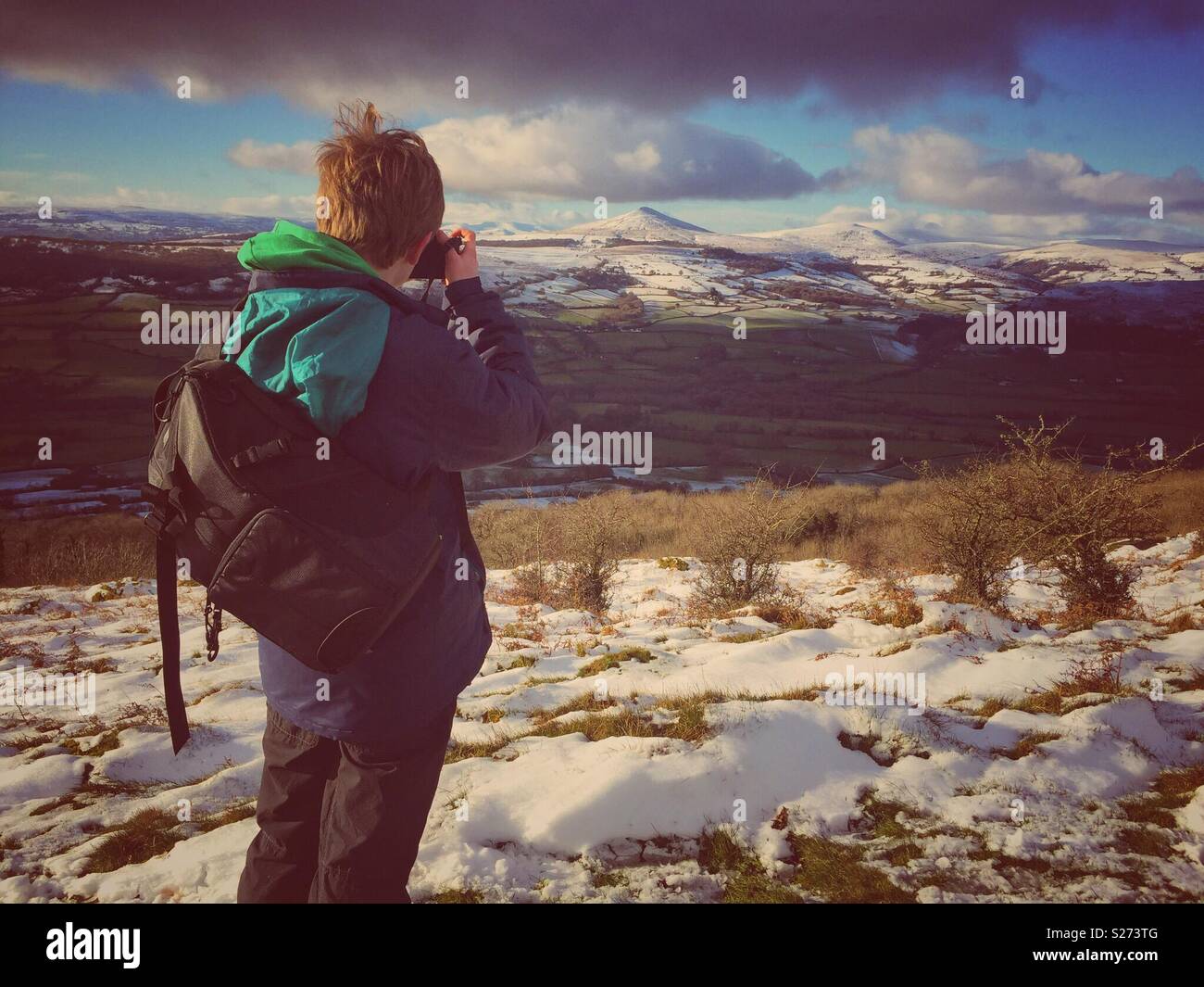 Ein kleiner Junge nimmt ein Foto von der Skirrid Berg, der Schnee Sugarloaf Mountain in der Nähe von Abergavenny, Brecon Beacons, Wales, Großbritannien Stockfoto