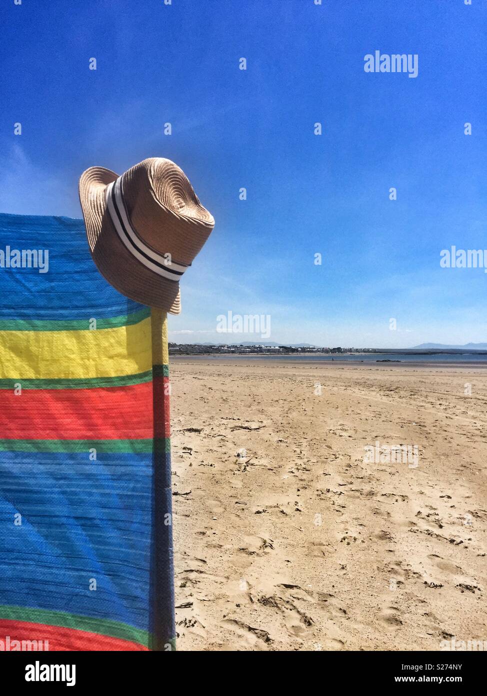 Panama Hut an der Ecke des gestreiften bunte Windbreaker am Strand von Rhosneigr, Anglesey, North Wales, UK Stockfoto