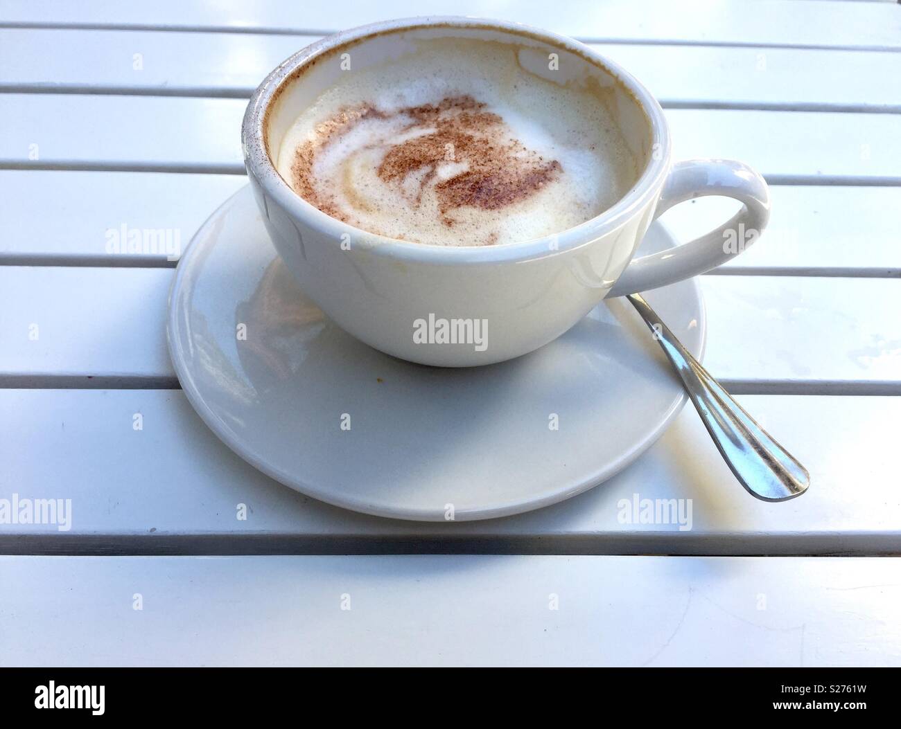 Eine Tasse Cappuccino auf einem weißen Lattenrost Tabelle Stockfoto