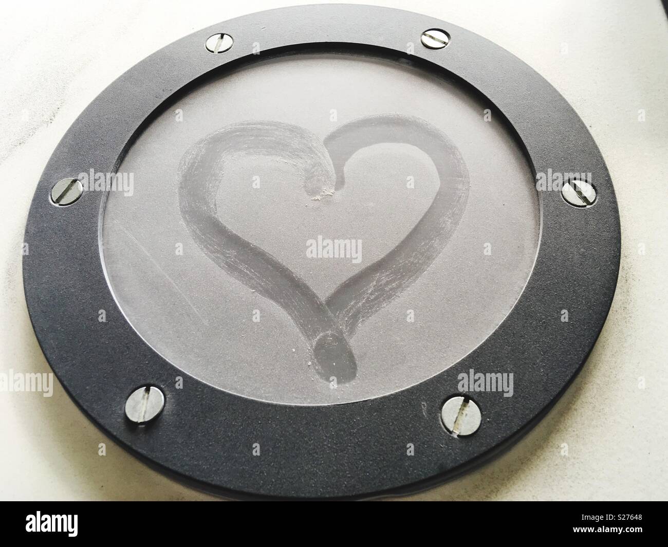 Ein Herz, das in den Staub eines runden Fensters gezogen ist Stockfoto