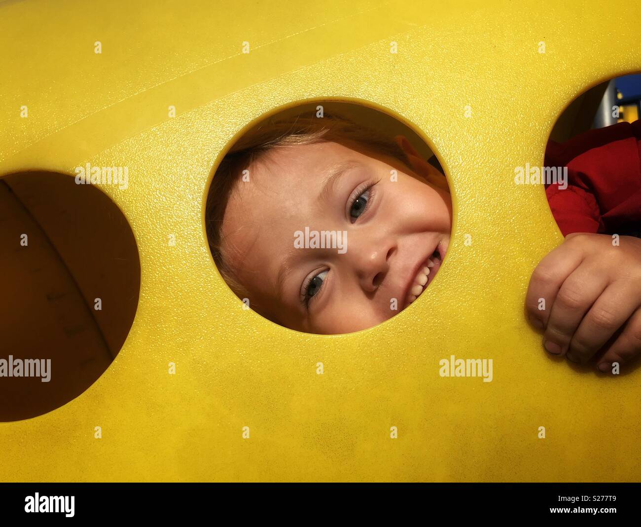 Kind spähen durch ein Loch auf dem Spielplatz Stockfoto