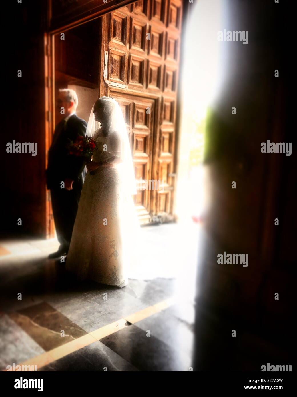 Eine Braut und ihr Pate steht an der Tür während einer Hochzeit in der Kirche in Coyoacan, Mexiko - Smartphone-aufgenommenes Stockfoto