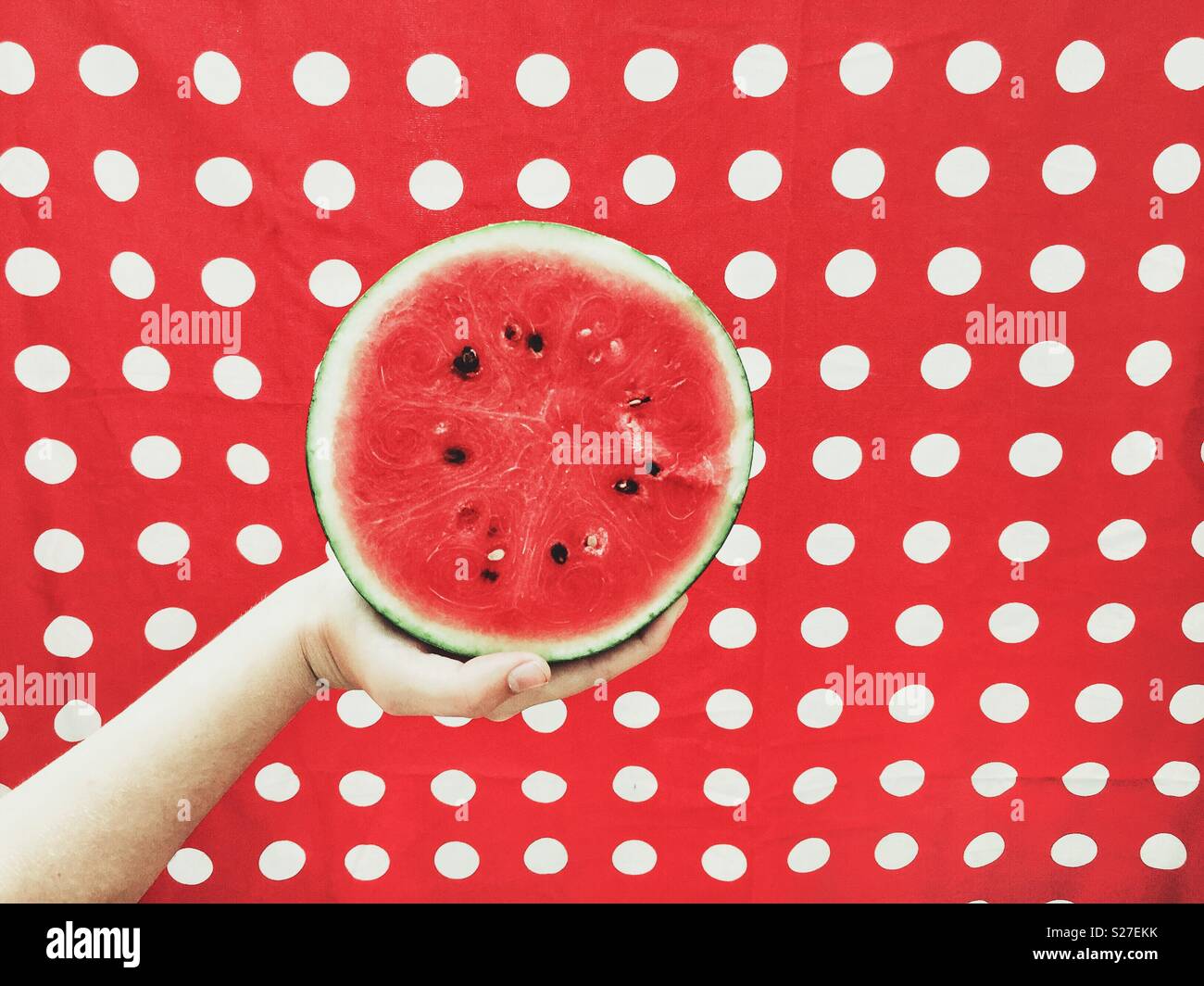 Hand, die halbe Wassermelone auf rotem Hintergrund Stockfoto