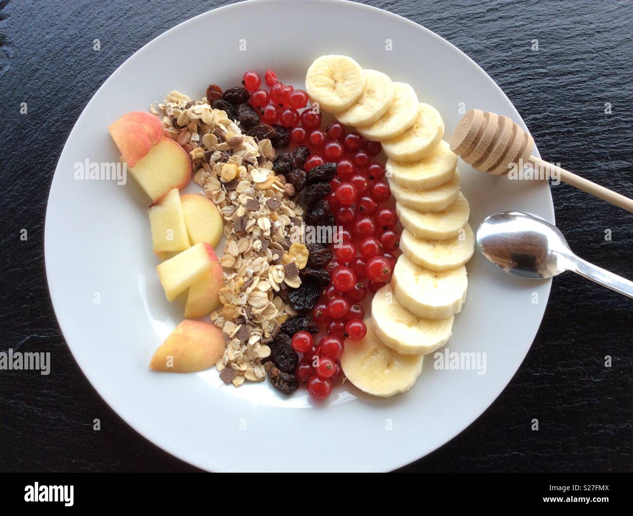 Erhöhten Blick auf weiße Platte mit einem hölzernen Löffel Honig, Getreide und Obst zum Frühstück Stockfoto