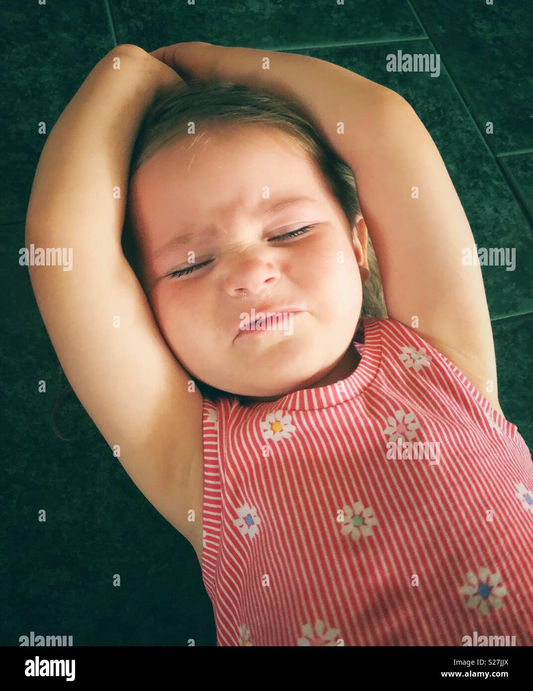 Kleinkind Mädchen mit einer Grimasse Ausdruck gefangen, während Sie einen Wutanfall auf dem Boden Stockfoto