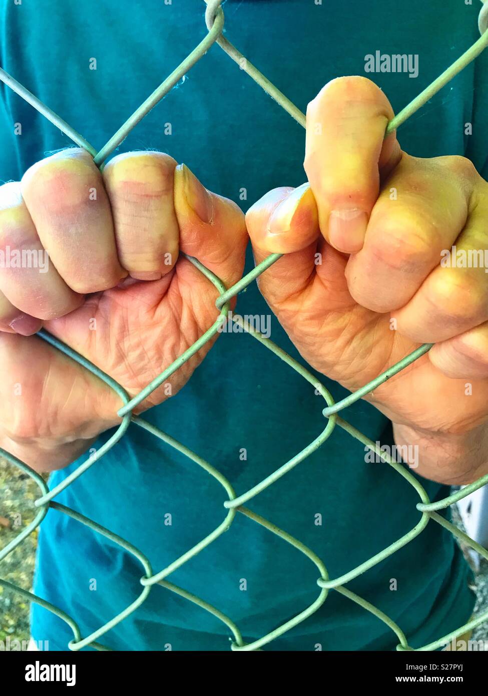 Zwei Hände halten Maschendrahtzaun - Smartphone-aufgenommenes Stockfoto