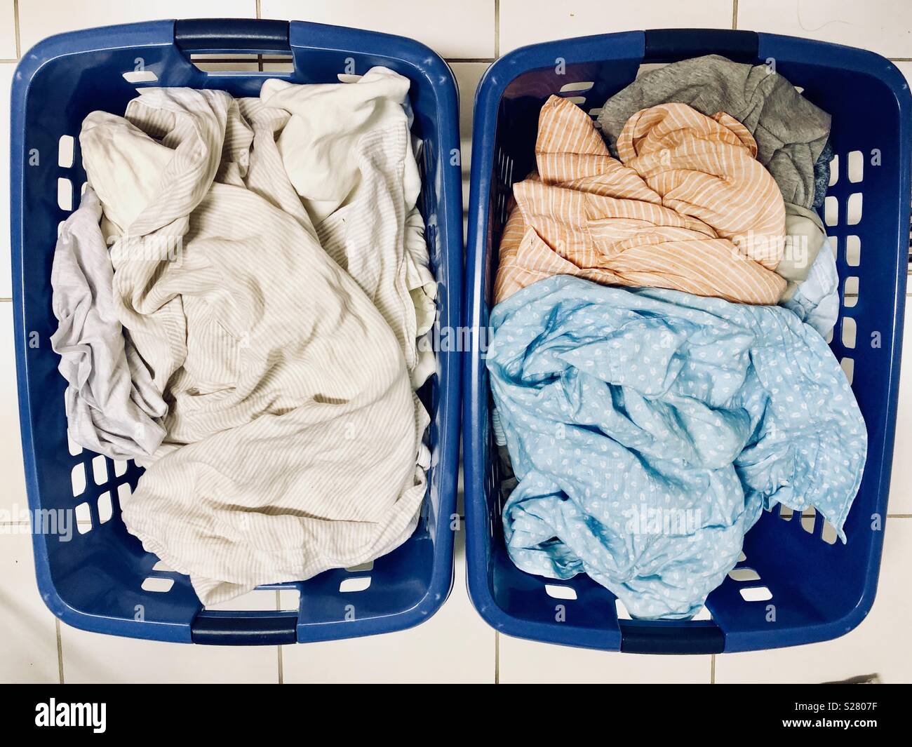 Wäschekörbe voller weiße und farbige Kleidung - Smartphone-aufgenommenes Stockfoto