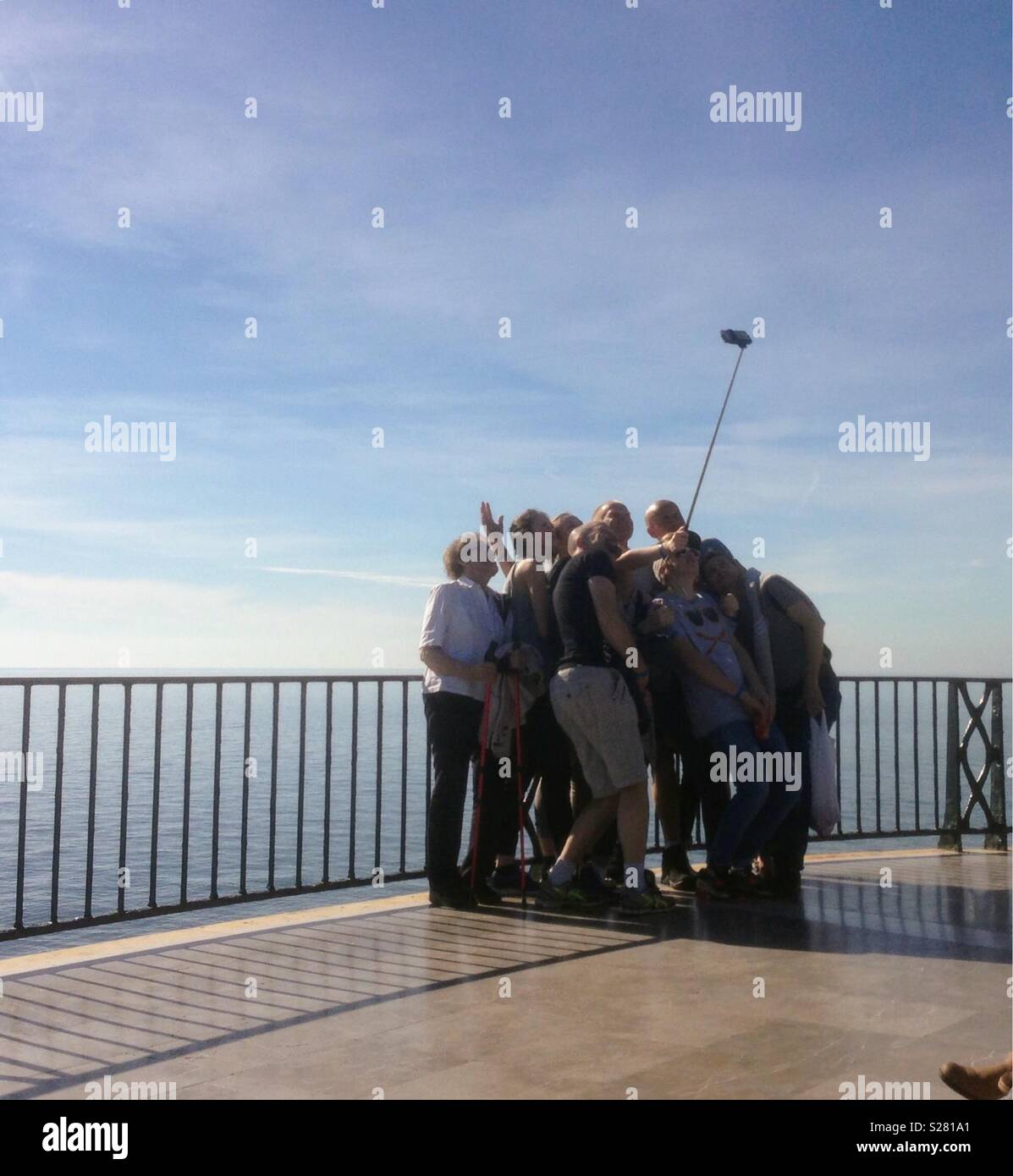 Gruppe von Personen posiert für ein Selfie-Foto mit einem Selfie-Stick. - Smartphone-aufgenommenes Stockfoto