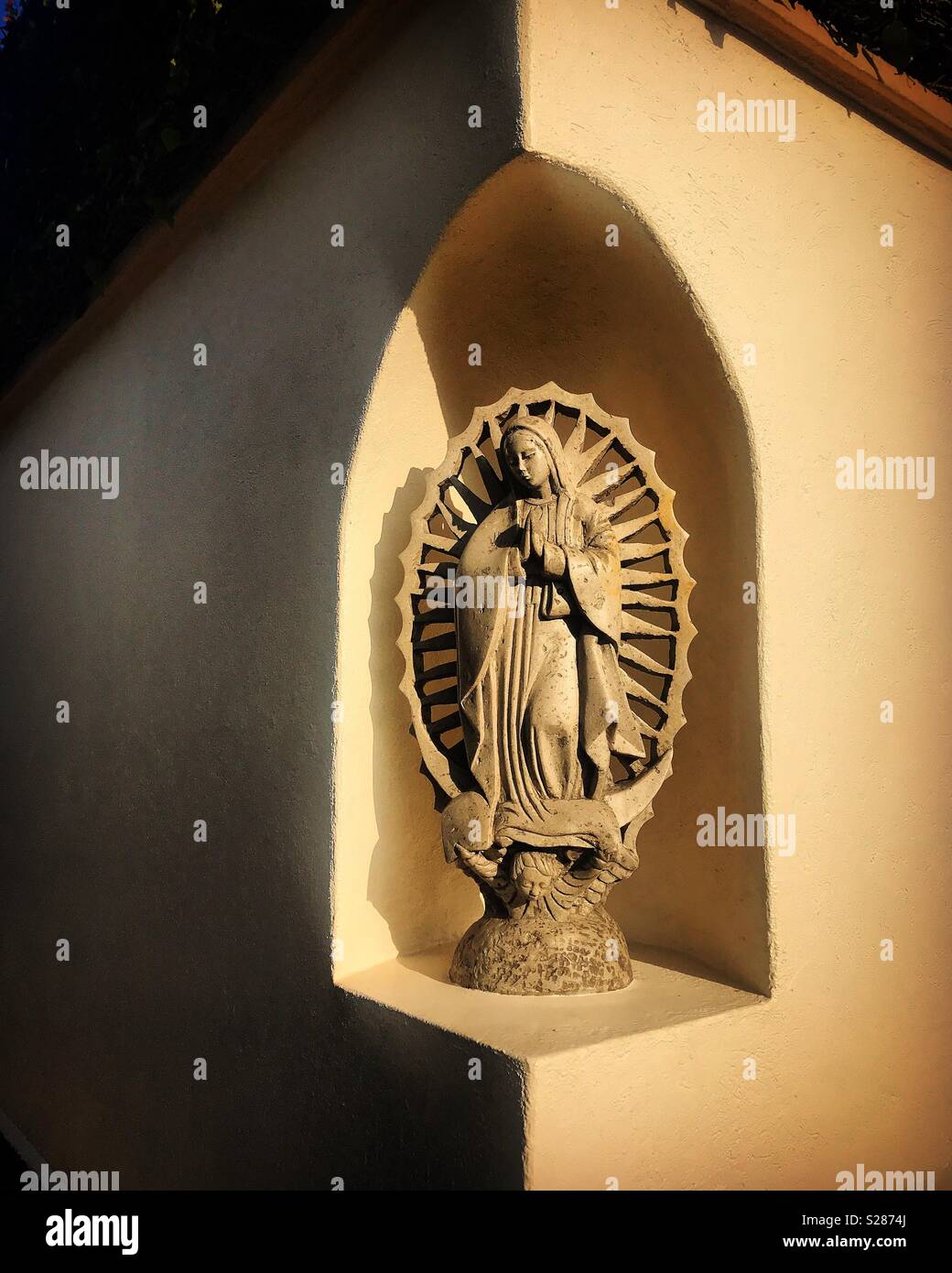 Eine Skulptur der Jungfrau von Guadalupe, die von der Sonne in einer Heimat von Coyoacan, Mexiko beleuchtet Stockfoto