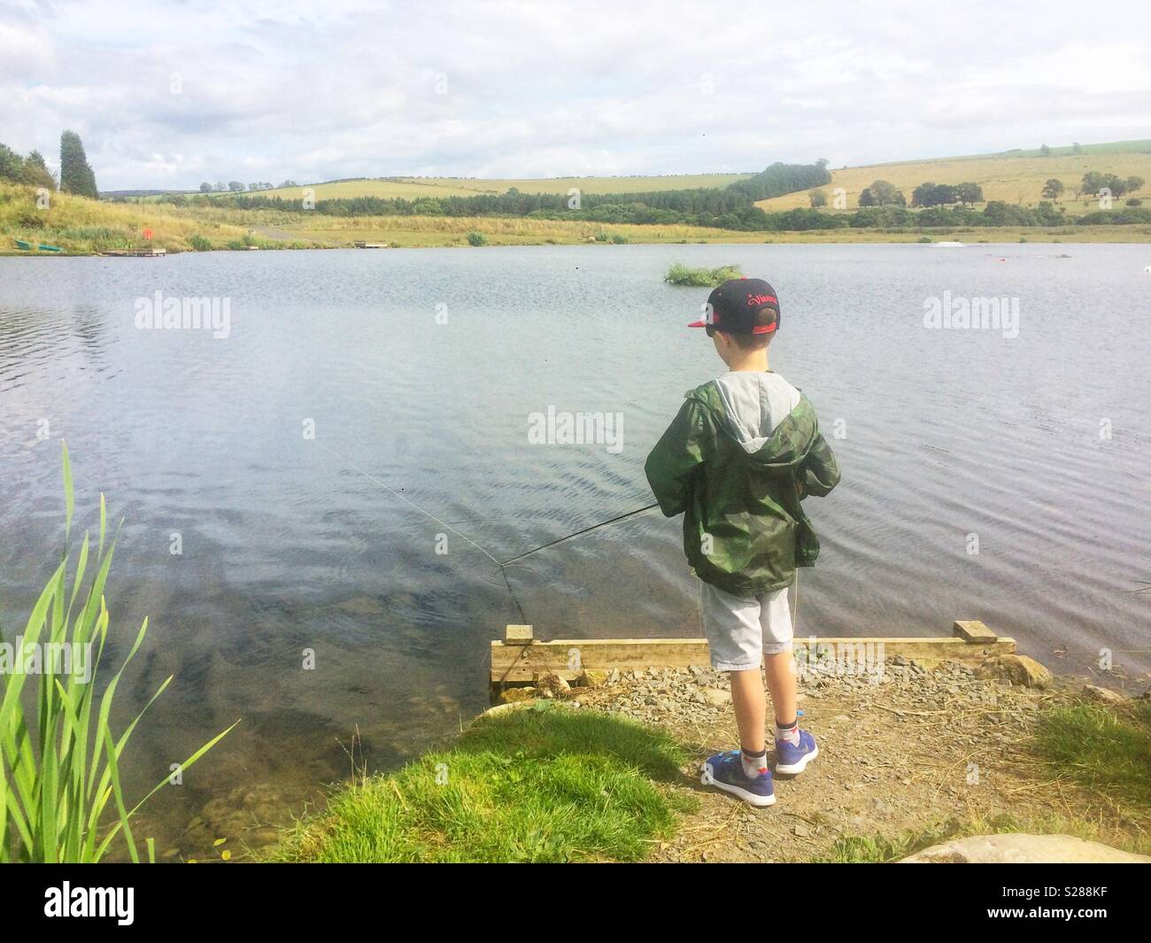 Neun Jahre alten Jungen Fliegenfischen auf Forellen in Thrunton lange Crag Forellenpacht, Northumberland, England, Vereinigtes Königreich Stockfoto