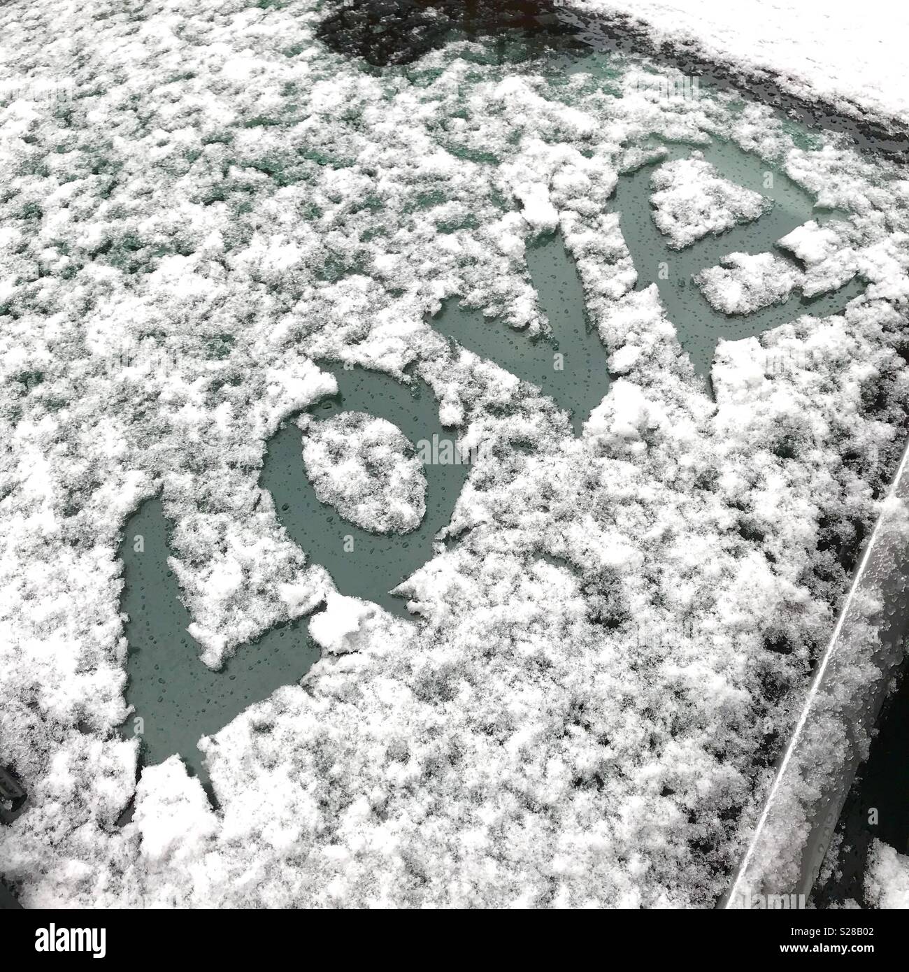 Das Wort Liebe im Schnee auf einem Auto geschrieben Stockfoto