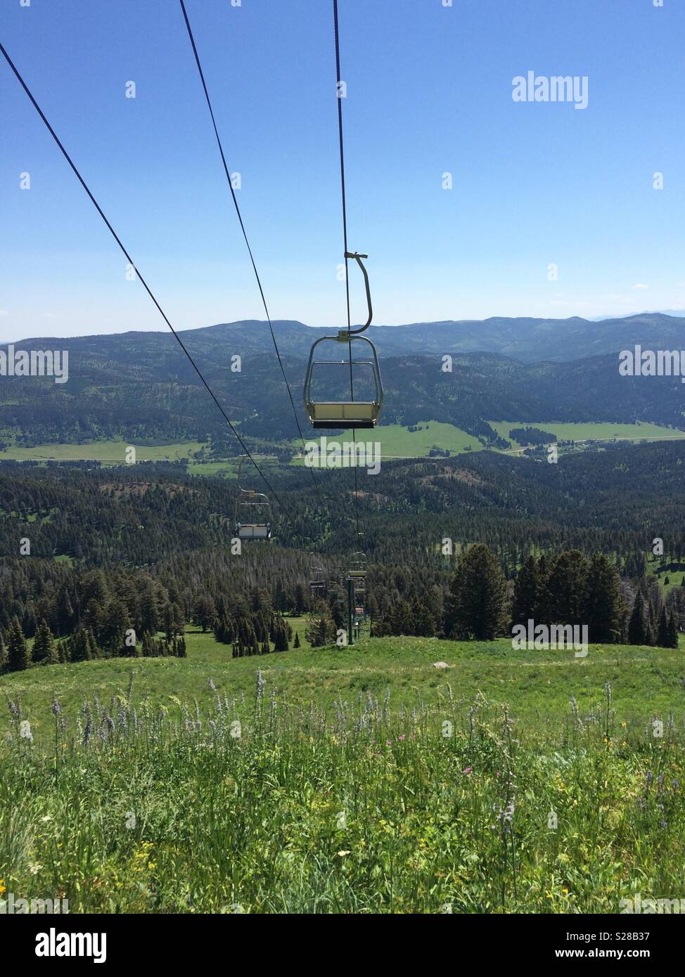 Stationäre Skilift Sessel und Kabel am Berghang im Sommer Stockfoto