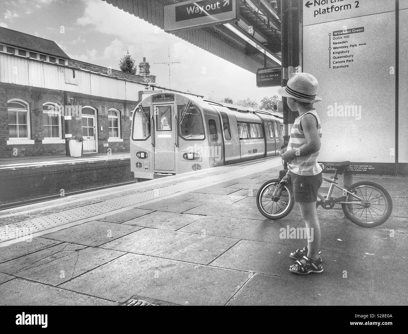 Ein Junge mit seinem Fahrrad an die nahende Jubilee Line Zug suchen, London Stockfoto
