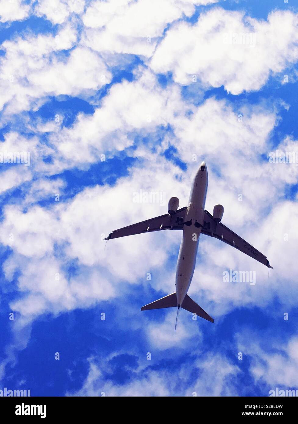Pkw Flugzeug fotografiert von unten mit blauem Himmel und weißen Wolken im Hintergrund. Stockfoto