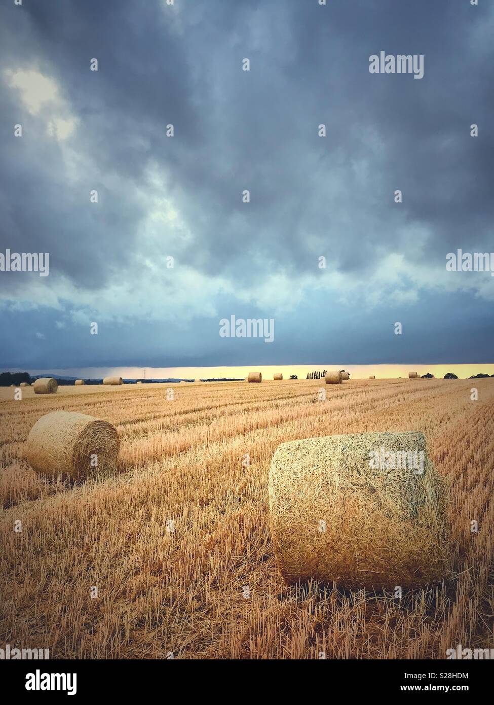 Strohballen auf einem Feld unter Gewitterwolken Stockfoto