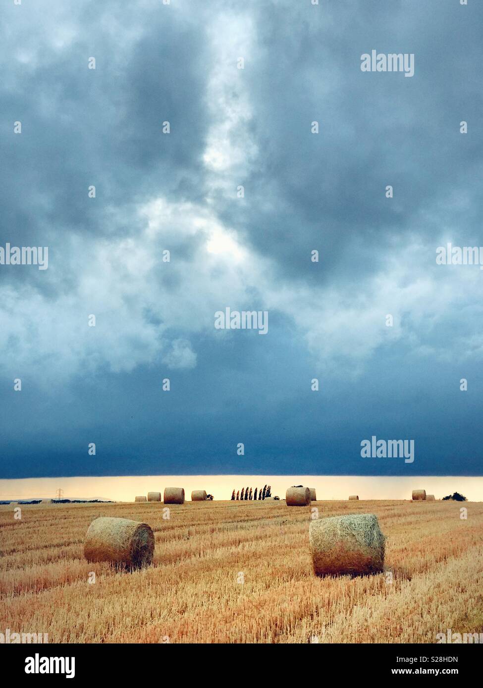 Strohballen auf einem Feld unter Gewitterwolken Stockfoto