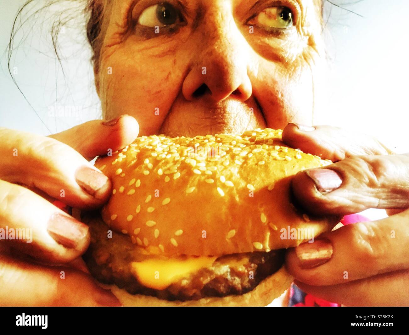 Ältere Frau essen Käse Burger Stockfoto